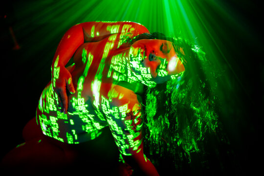 Pregnant white woman illuminated by artistic green numeric projections
