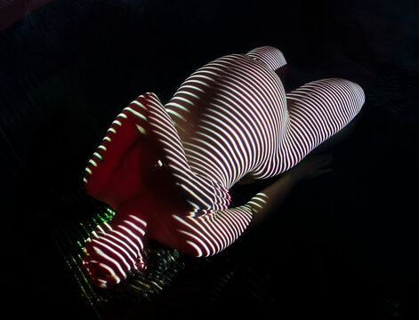 Pregnant white woman with striped light body art lying