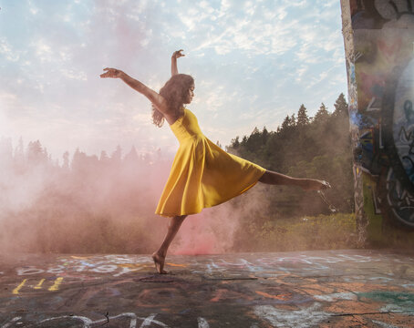 South Asian dancer in yellow dress performing outdoors near graffiti