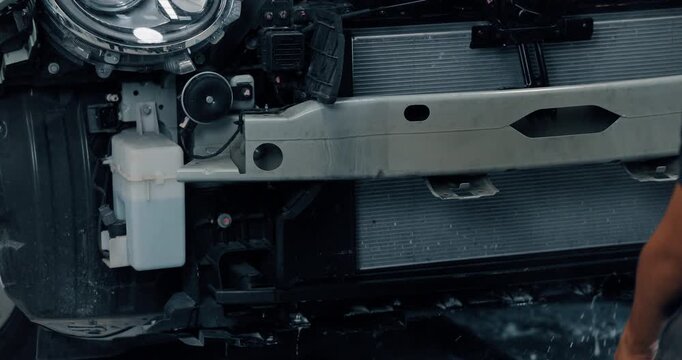 Mechanic cleaning EV radiator and condenser by spraying water and blowing air dry in service garage
