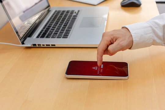 Smartphone security warning on wooden desk with hand reaching to device