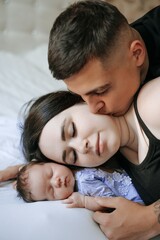 Fototapeta premium A family portrait: mom, dad, and a small child; a happy family with a newborn baby at home.