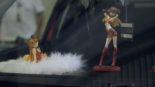 Car dashboard with anime girl Asuka figurine from Evangelion at car exhibition