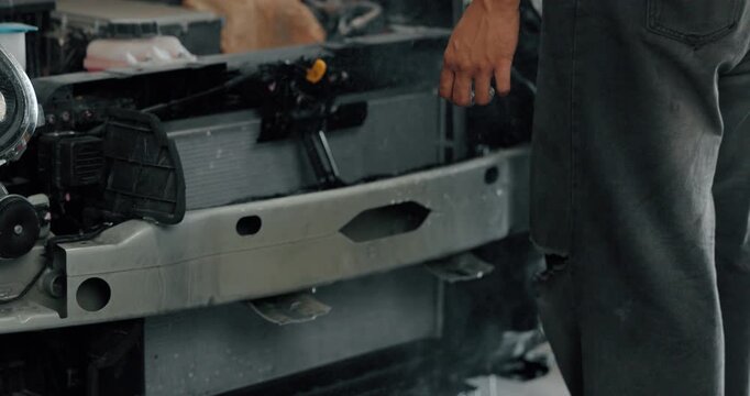 Mechanic cleaning EV radiator and condenser by spraying water and blowing air dry in service garage