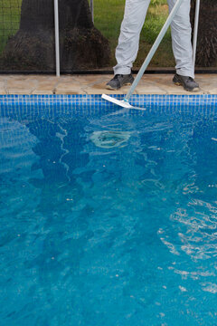 Close up of worker cleaning swimming pool tiles with long handled brush