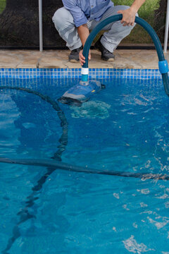 Close up of pool maintenance worker using cleaning machine with copy space