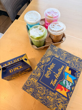 Saskachewan, Canada - August 20, 2026: Harry Potter x Tim Hortons limited edition collaboration box and 10-pack timbits with four colorful iced drinks in cardboard carrier on table