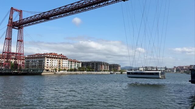 Suspended gondola of the Vizcaya transporter bridge moving away from the bank across the estuary.