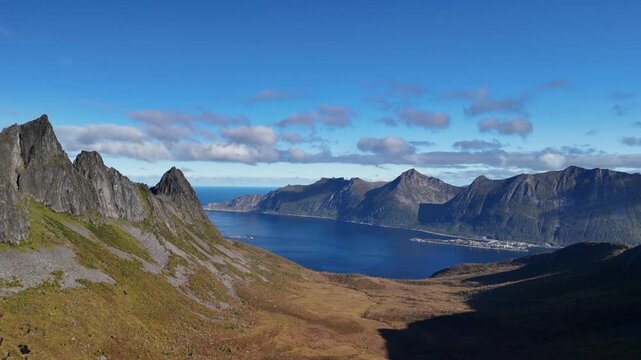 Cinematic 180 degree aerial drone rotation revealing majestic mountain and deep blue fjord landscape in Norway