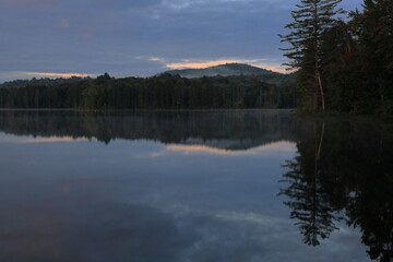 Fototapeta premium Skyline of remote wilderness shoreline reflected in a pond at dusk