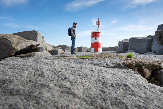 Man standing near a red and white lighthouse