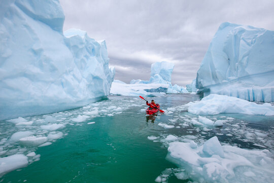 kayaking in Antarctica, extreme sport adventure expedition, man paddling on kayak between ice in Antractica in Iceberg Graveyard