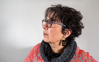profile portrait of mature woman with short curly hair and glasses looking away © Philipimage