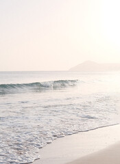 Soft pastel beach with turquoise wave and white sea foam in bright hazy light, minimal Mediterranean seascape © Alina Mir