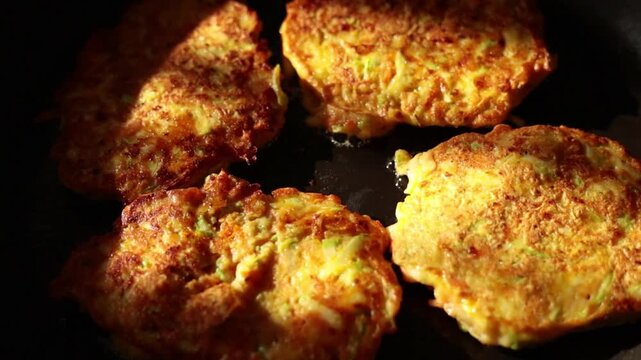 Healthy vegetable fritters frying in a skillet. Zucchini and carrot patties cooking on a stove. Homemade vegan food recipe.