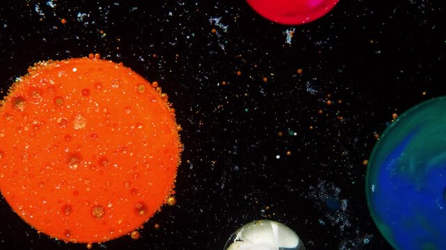 An abstract cosmic composition: multicolored spheres simulating planets float against a black background, and a scattering of small particles creates the effect of star dust and the depth of space.