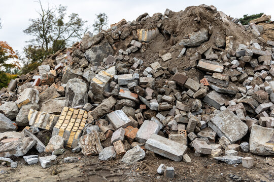 Large pile of construction rubble contains broken concrete, bricks, paving stones and soil at demolition site. Mixed debris illustrates building waste, cleanup, recycling and urban redevelopment