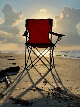 Empty red chair on the beach at sunrise