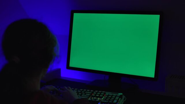 Girl of Green Screen Display PC at Desk in Home at Night. Desktop PC Monitor With Green Mockup, Chroma Key, Working. Person Teenager Programer Typing Codes Mockup Computer. Software Development.