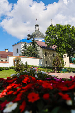 View of old city church through colorful flowerbed with blooming flowers, historic architecture, urban garden landscape.