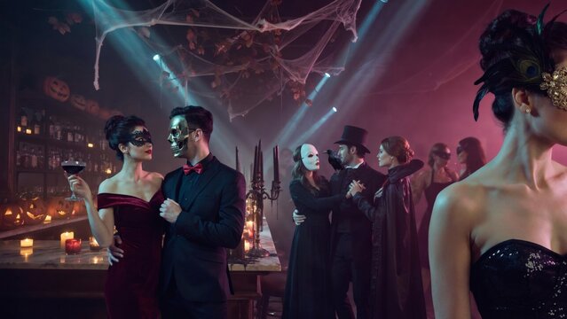 Halloween masquerade party celebration. People in fancy costumes and masks drinking cocktails. Spooky themed bar with candles and spider webs