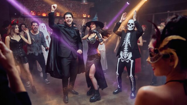 Halloween party celebration photo. People in vampire witch and skeleton costumes dancing