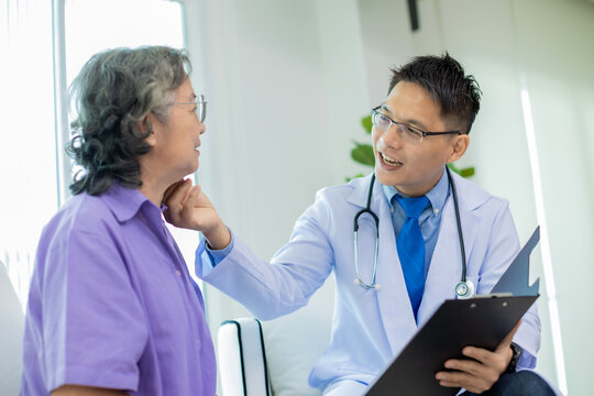Doctor assisting her old patient at nursing home. Caregiver helping senior patient sit on sofa. Friendly Doctor talking with patient at nursing home