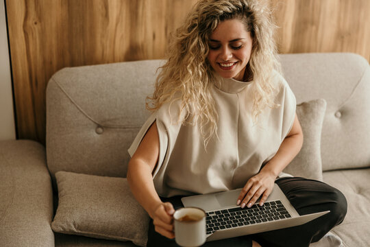 Woman working on laptop drinking coffee at home