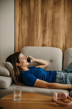 Young woman relaxing on couch making phone call
