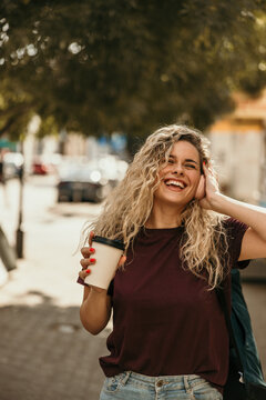 Happy woman enjoying music and coffee on city street