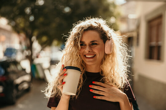 Happy woman enjoying music and coffee outdoors