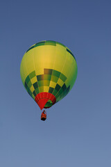 Fototapeta premium Colorful hot air balloon floats high against a deep blue sky with copy space. Leisure flight represents adventure, aspiration, freedom and discovery from above.