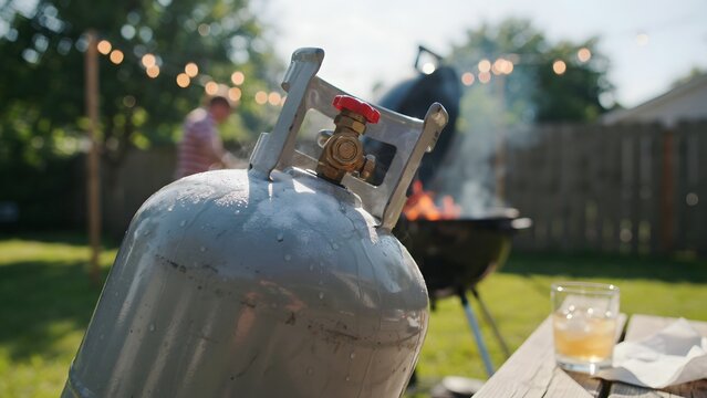 Portable propane tank ready for outdoor barbecue cooking in backyard setting