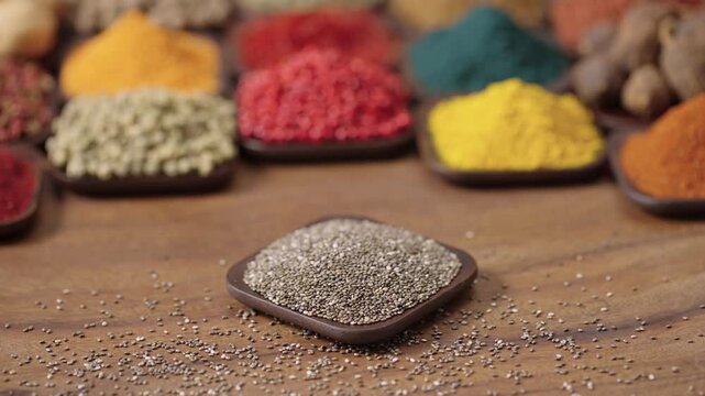 chia seeds salvia hispanica plants in a square bowl on a wooden table, surrounded by various spices and herbs.