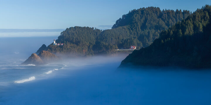 Beautiful wide panoramic view of a historic lighthouse on a misty rocky ocean coast at sunrise