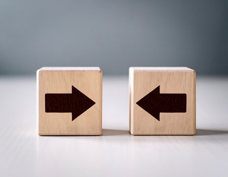two wooden cubes with arrow symbols pointing in opposite directions sit on white desk light dark wood blocks display contrast comparison business strategy decision choice change concept minimalist