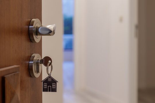 Open door to a new home with key and home shaped keychain. Mortgage, investment, real estate, property and new home concept