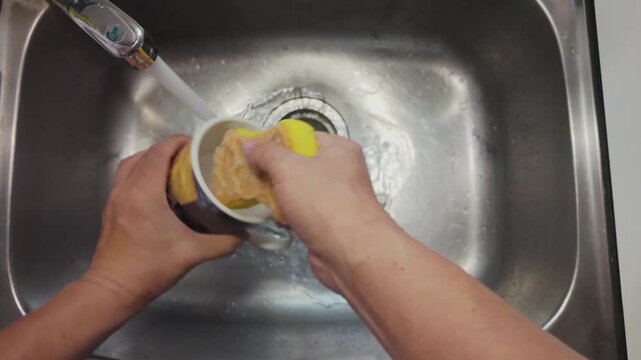 Washing a Glass with Soapy Water in Kitchen Sink