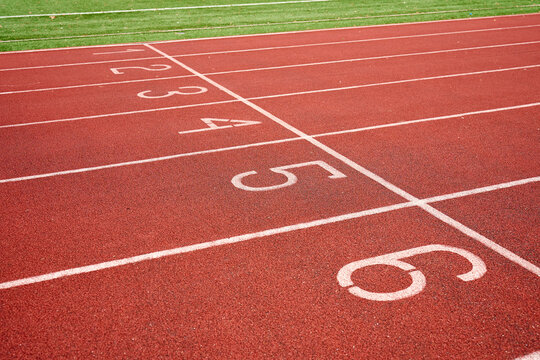 Empty red running track with numbered lanes at stadium