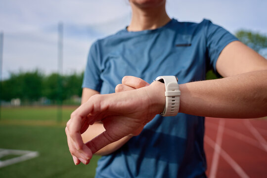 Woman checking smartwatch before starting a run at stadium