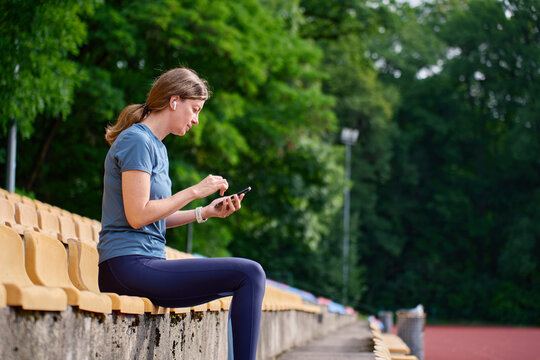 Woman using smartphone while resting on stadium seats