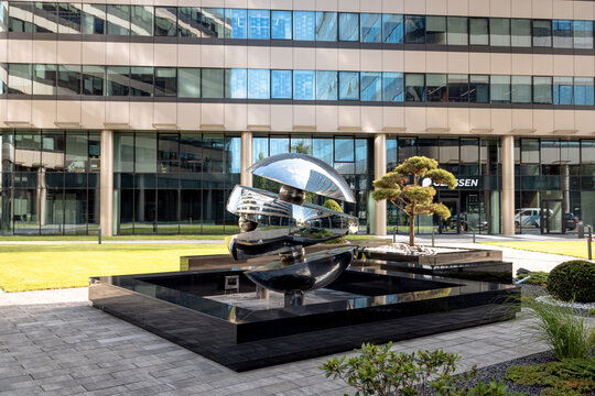 Krakow, Poland - July 22, 2026: Contemporary metal sculpture and landscaped public space among office buildings at Fabryczna City.