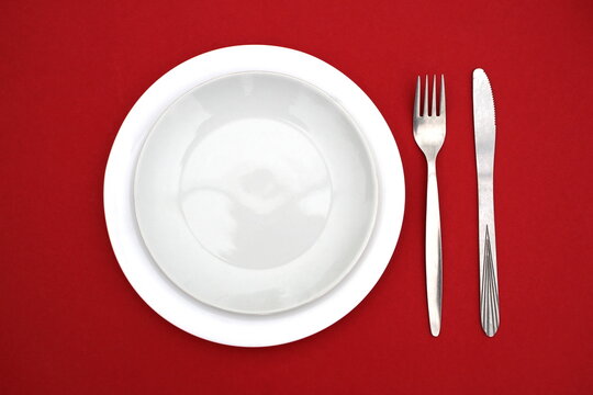 Plates with a spoon and a fork are set against a red background.