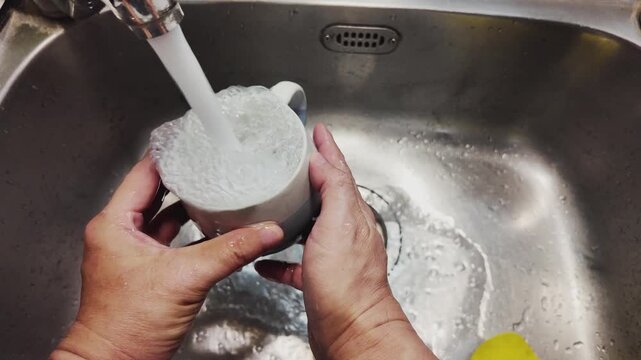 Washing a Glass with Soapy Water in Kitchen Sink