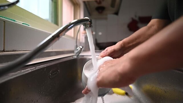 Washing a Glass with Soapy Water in Kitchen Sink