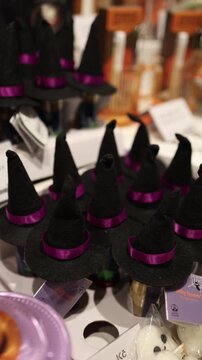 Vertical screen Halloween party decorations with miniature witch hats pumpkins and ghost figures displayed together in a store for festive seasonal celebrations
