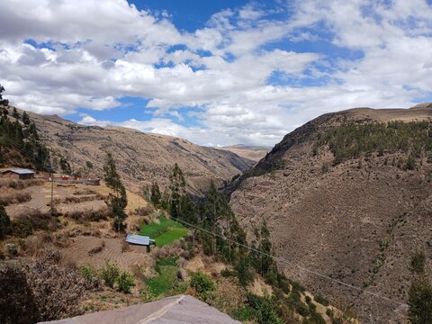 Valley with a distant river, mountains, forest, and a cloudy sky in the background in Surimana, Cusco, Peru.