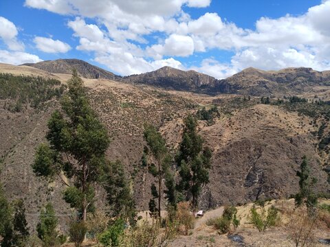 View of mountains and trees with a cloudy sky in the background in Surimana, Cusco, Peru.