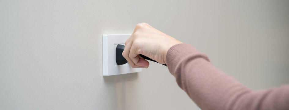 Close-up hands pull off electronic device plug after finish used.