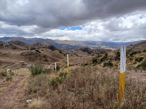 View of mountains and a path with a cloudy sky in the background in Cusco, Peru.